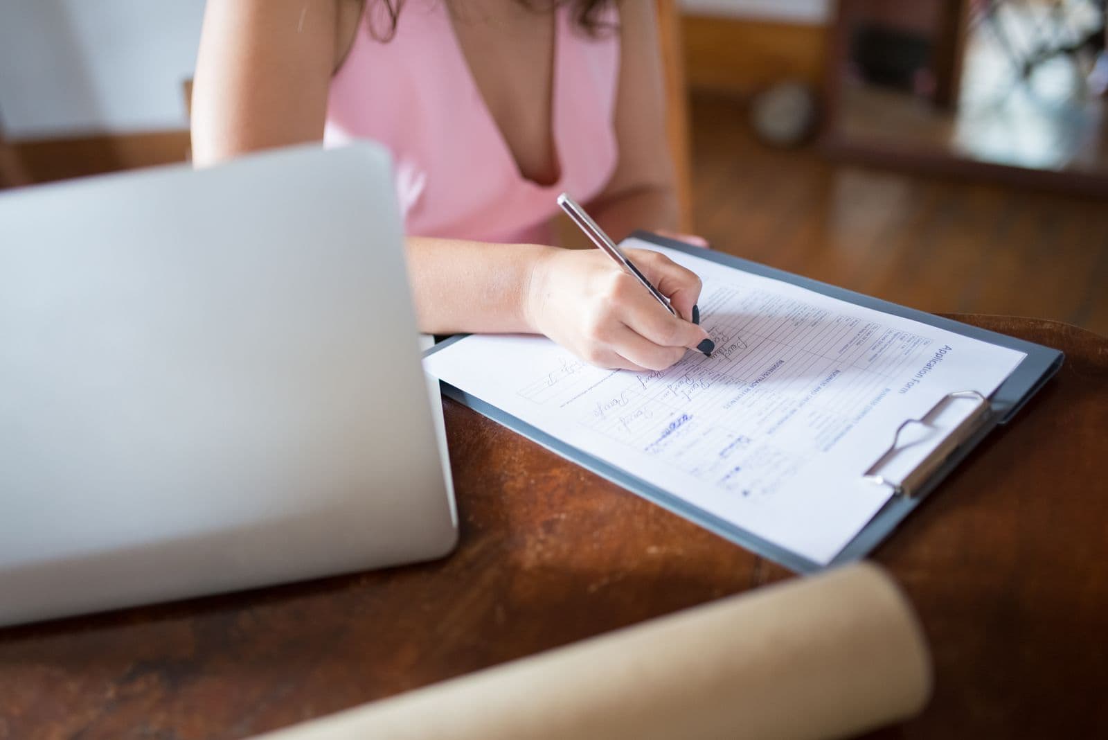 Aanvraagformulier wordt ingevuld naast een laptop en een opgerolde tekening